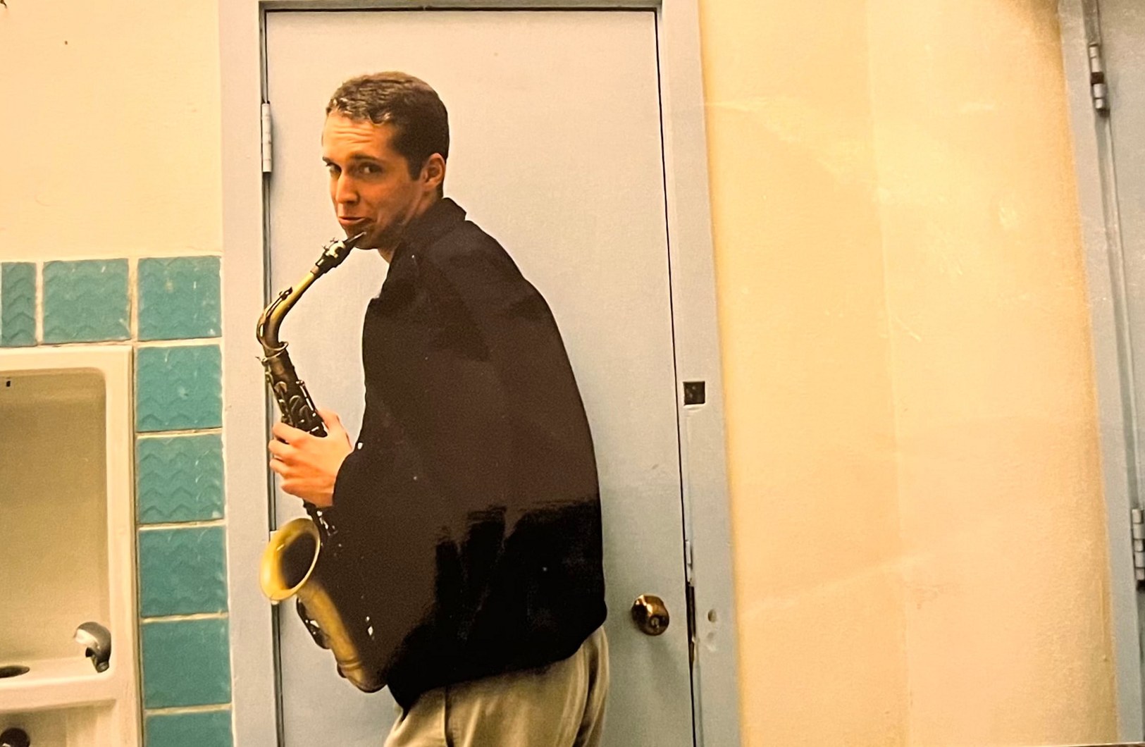 A Byars brother playing saxophone in a tiled school hallway