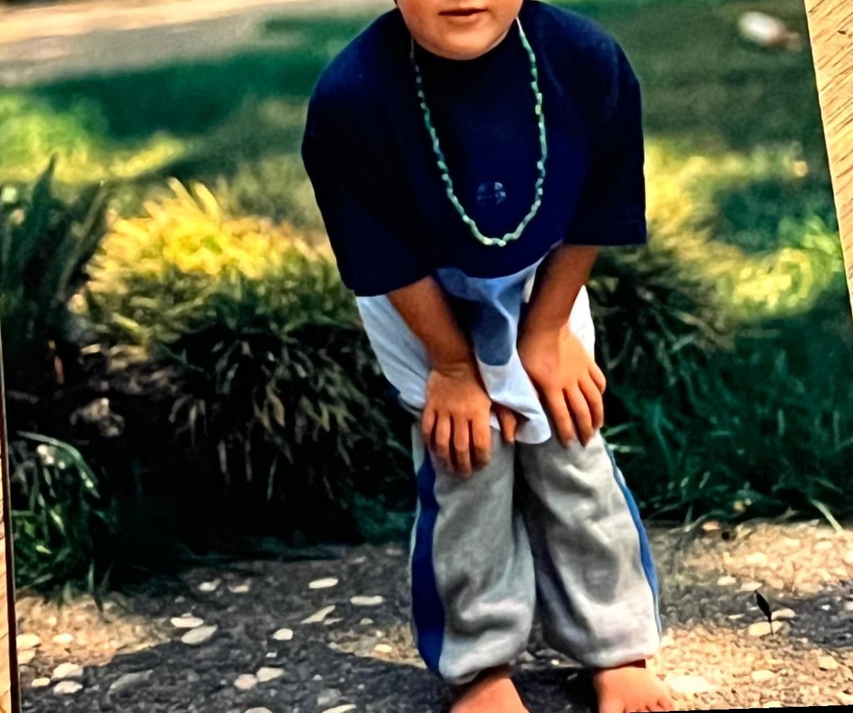 A little Byars brother standing in the front yard on a sunny afternoon
